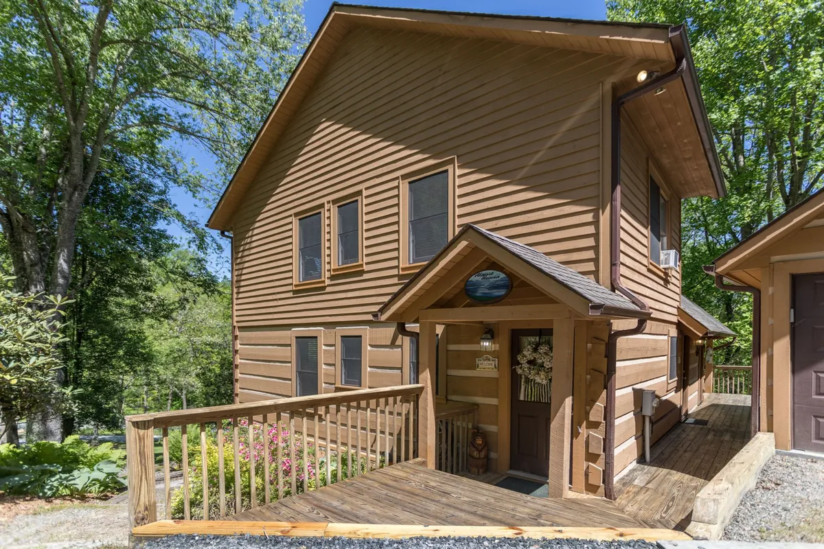 A charming view of the log cabin’s wooden entrance, adorned with flower decor and natural surroundings. The inviting porch hints at cozy moments, from morning coffee to evening stargazing, and suggests a warm welcome to an intimate retreat.