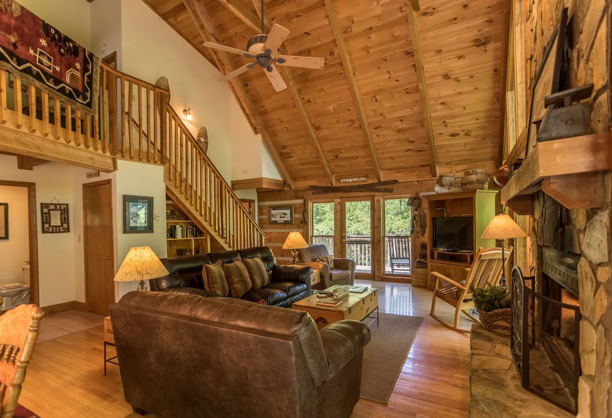 A spacious living area with a stone fireplace, comfortable seating, and large windows framing views of nature. The setting is warm and inviting, perfect for cozy evenings spent planning the next day's adventures or relaxing after time outdoors.